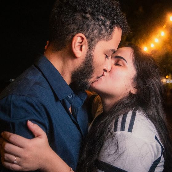 Carla e Rodolfo se beijando sob as luzes da noite